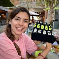 Nancy smiling at Sip + Stitch with her Ghosts Halloween hat in progress, rows of Citrus Pop and Vanilla ghosts on a Black Licorice background